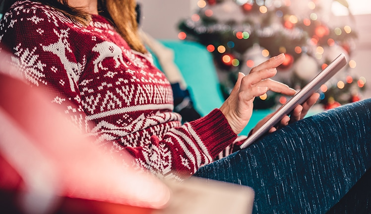 Women reading on tablet with Christmas tree in background